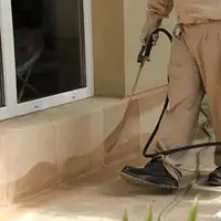 General pest control technician spraying exterior perimeter around a home in Bakersfield, CA